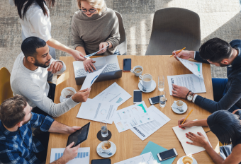 a group of payroll professionals discussing business around a desk