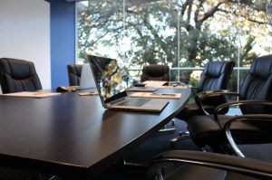 payroll office boardroom meeting table with chairs and an open laptop