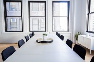 White conference room table in a payroll office surrounded by bright open windows